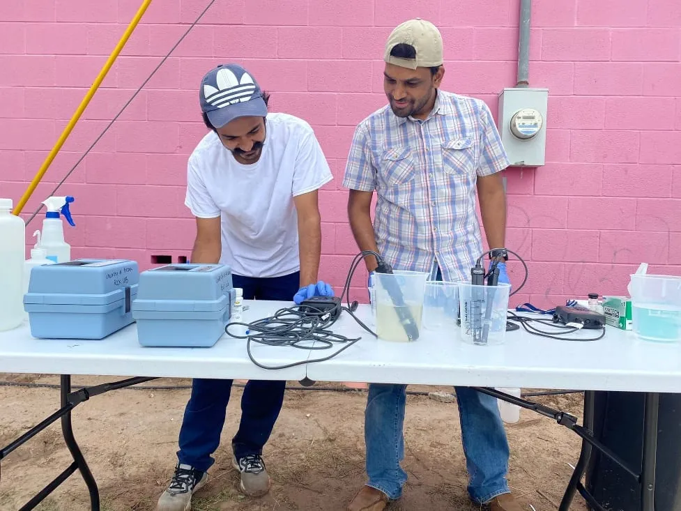 Two researchers running water-quality tests at an outdoor station